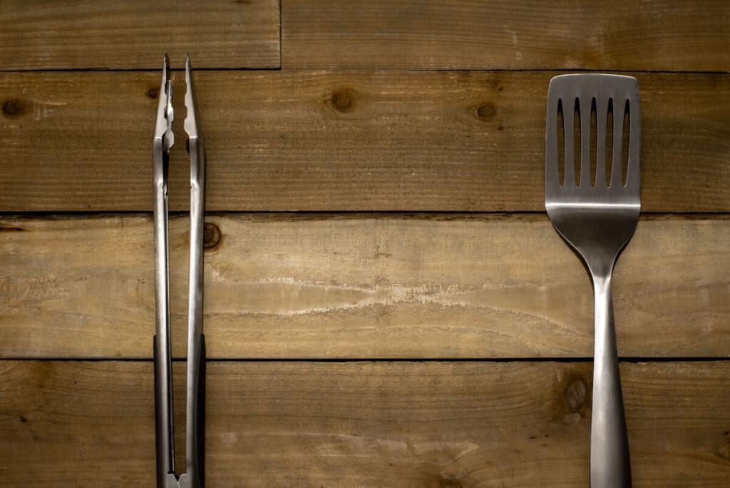 Spatuland tongs on a wooden surf.