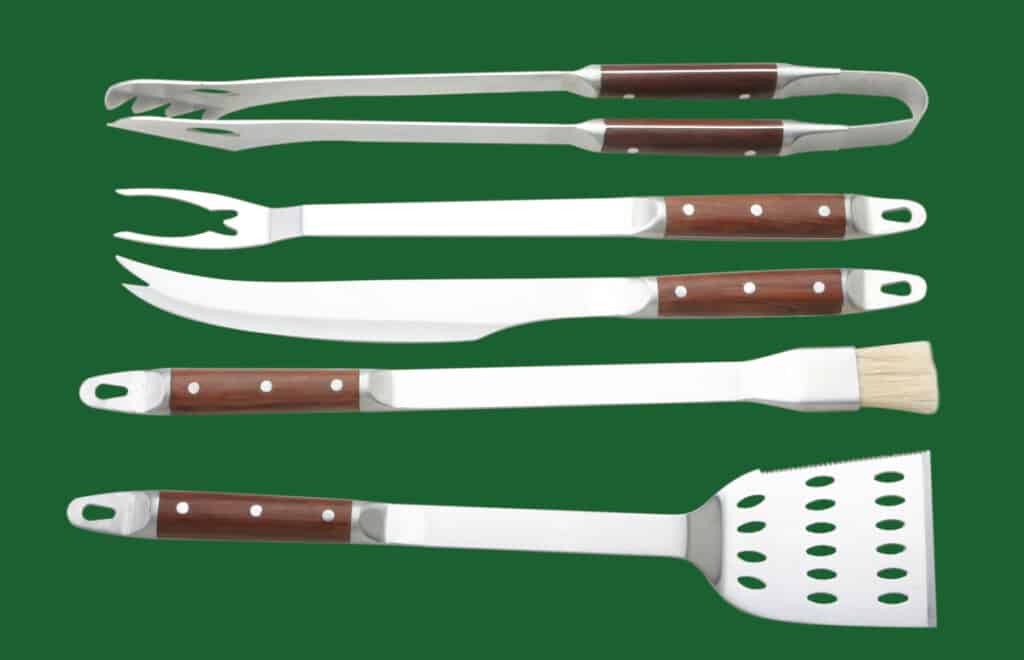 A BBQ tool set laid out on a green surf.