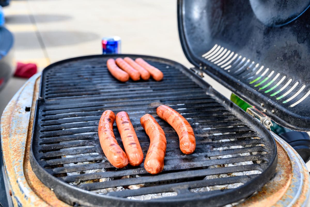  Hotdogs cooking on a portable gas gr.