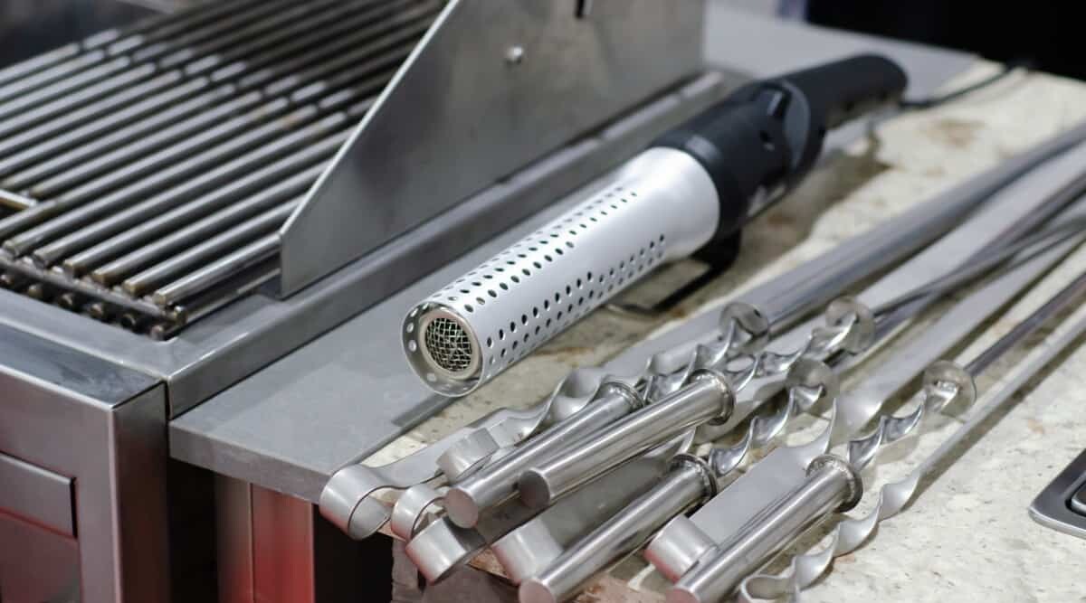 Grilling accessories, a Looftlighter and some kebab blades, next to a high quality, stainless steel grill.