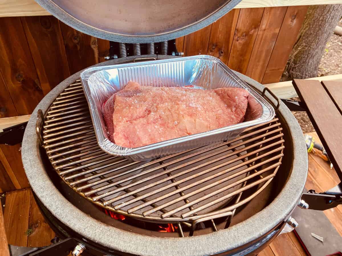 A large cut of pork being roasted on a kamado gr.