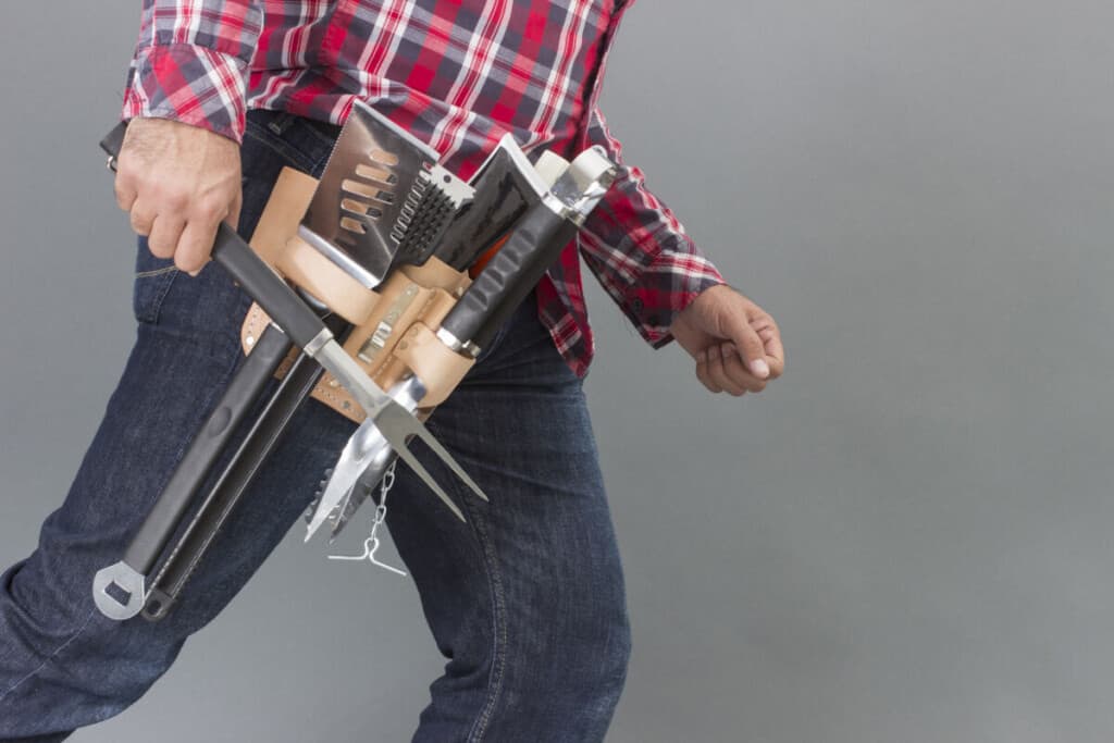 A man with a full tool belt of grilling to.