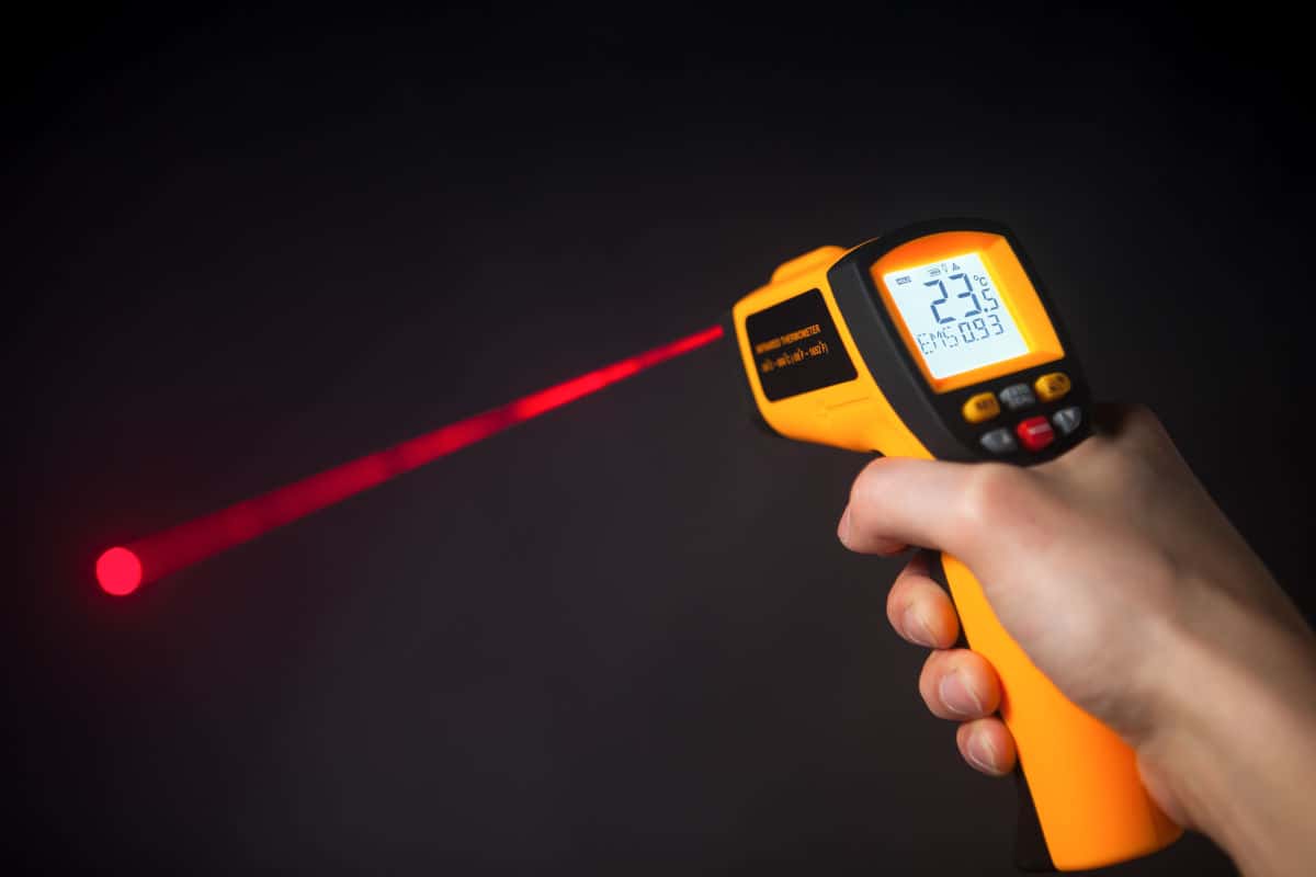 An infrared thermometer firing a red laser onto a black surface to take t.