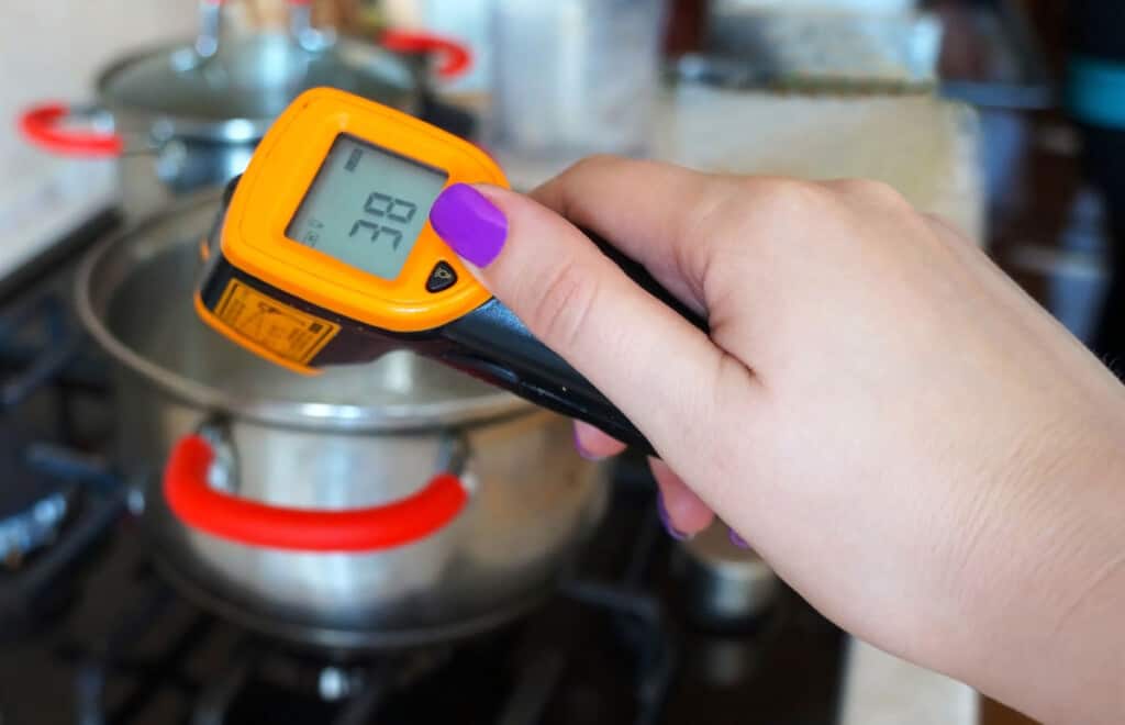 An infrared thermometer measuring the heat from a pan on a hob