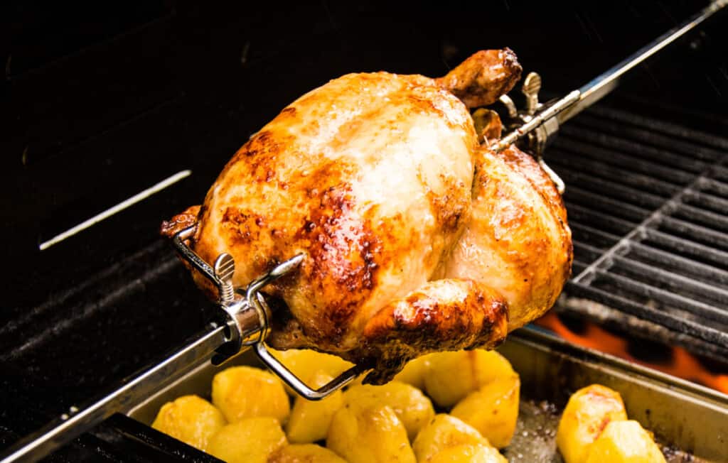 Z chicken being cooked rotisserie, with drippings going onto potatoes
