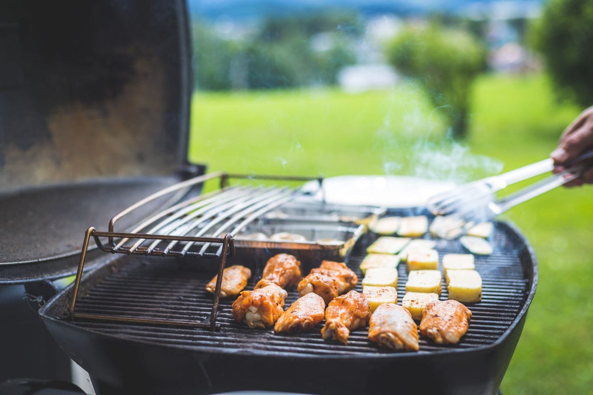 Close up of chicken and vegetable son a gas grill, in a fi.