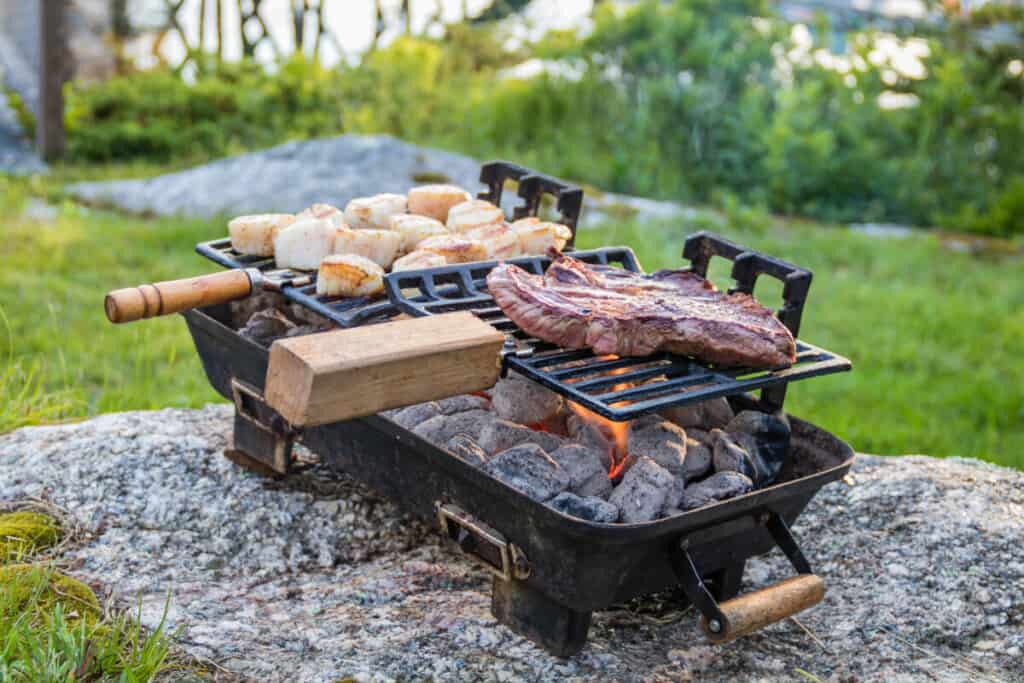 A portable hibachis grill set on a rock in a fi.