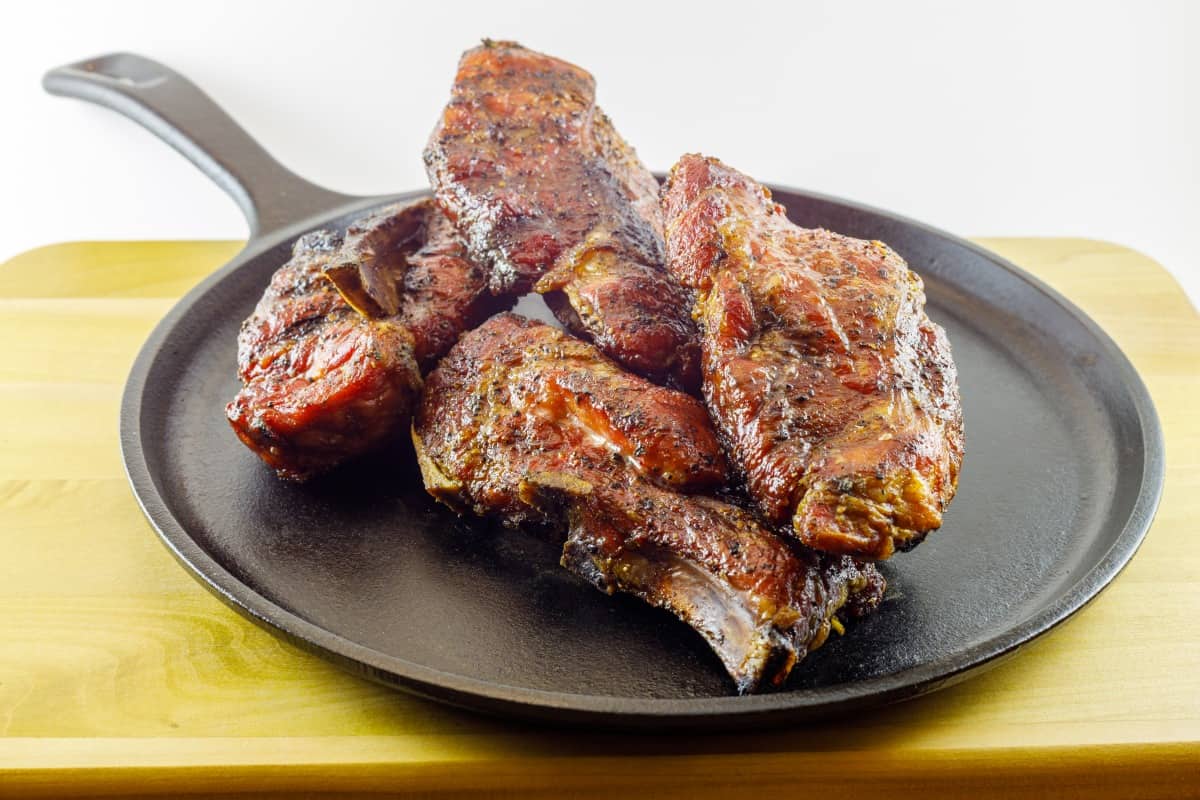 Smoked country style pork ribs served on a seasoned cast iron skil.