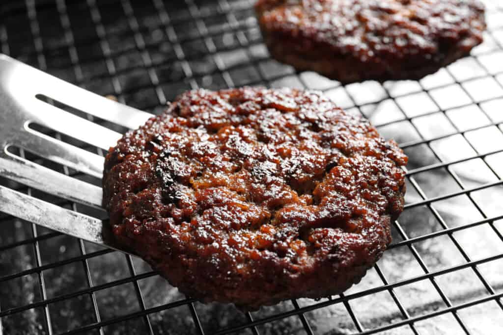 A apatula flipping a burger on a gr.