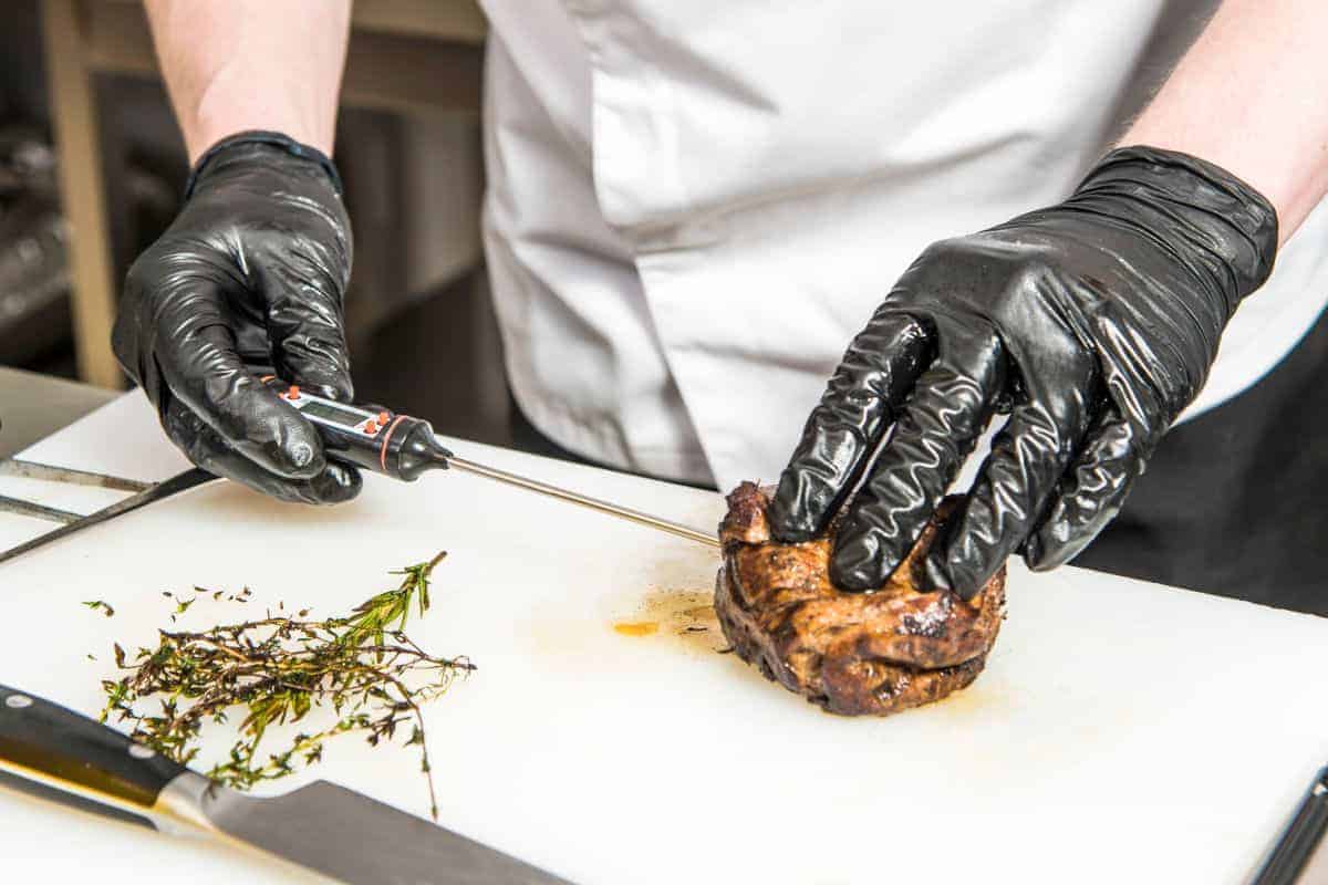 using an instant read thermometer to measure the internal temperature of cooked meat