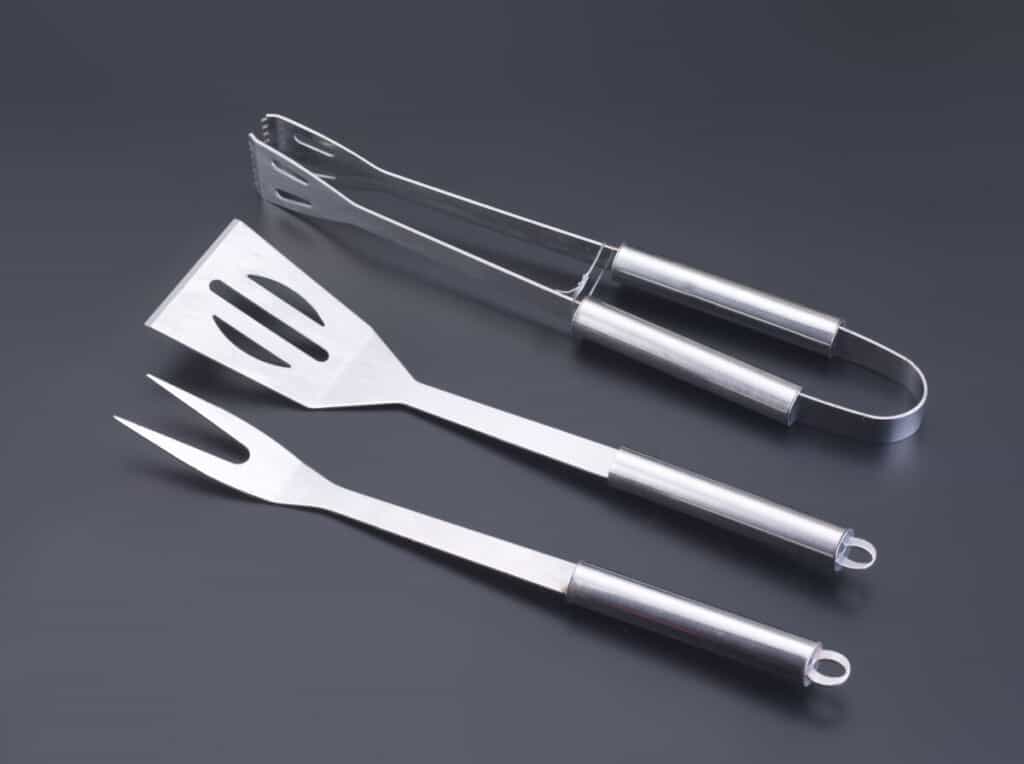 3 piece grilling tool set on a dark surf.
