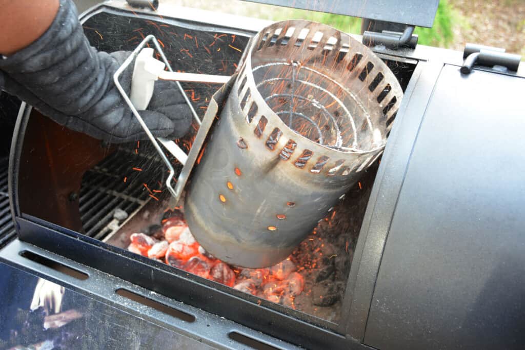 charcoal being emptied into the firebox of a smoker