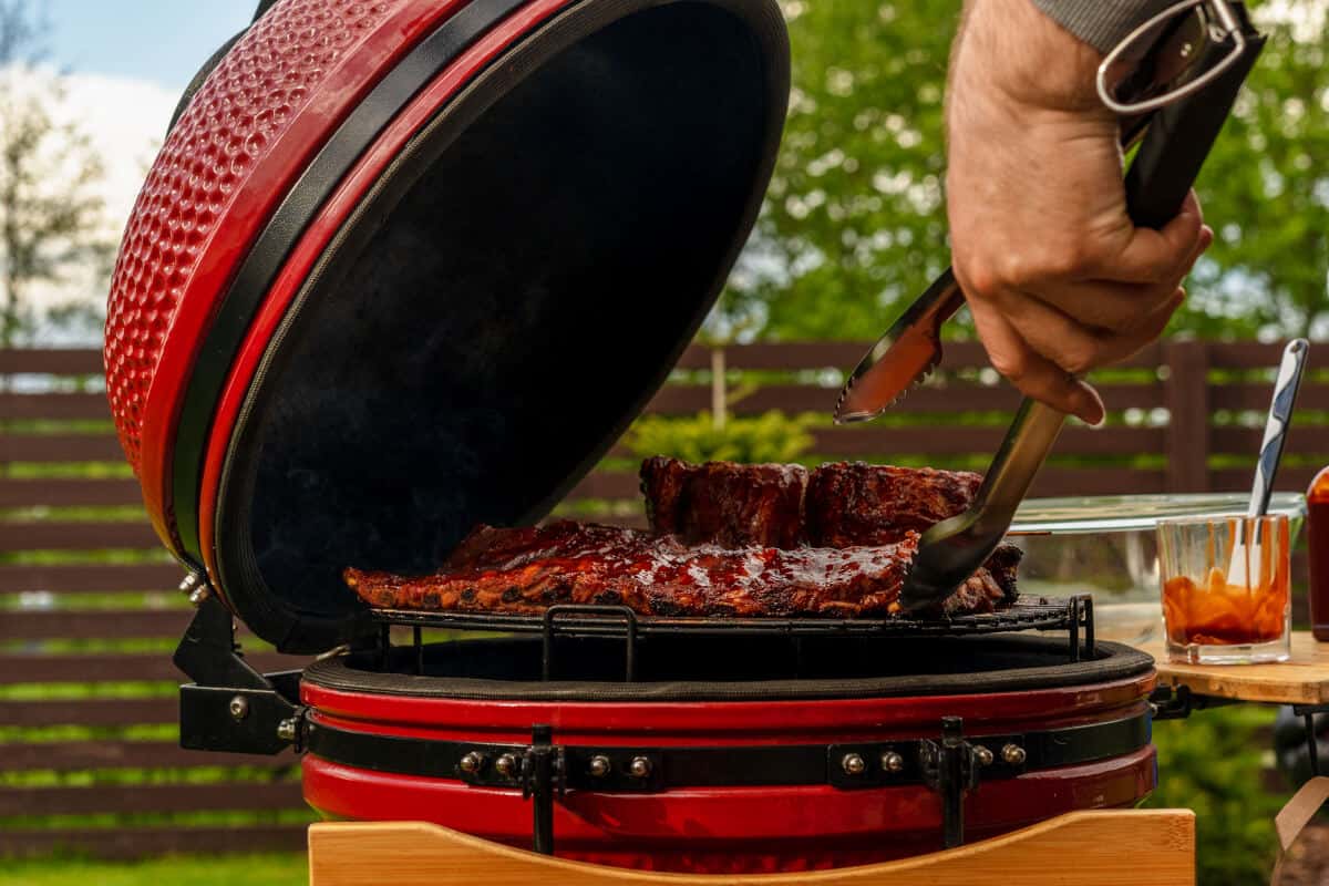 Side view of an open kamado grilling some me.