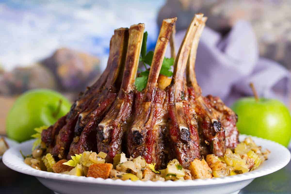 A pork crown roast in a white shallow bowl, with mixed .