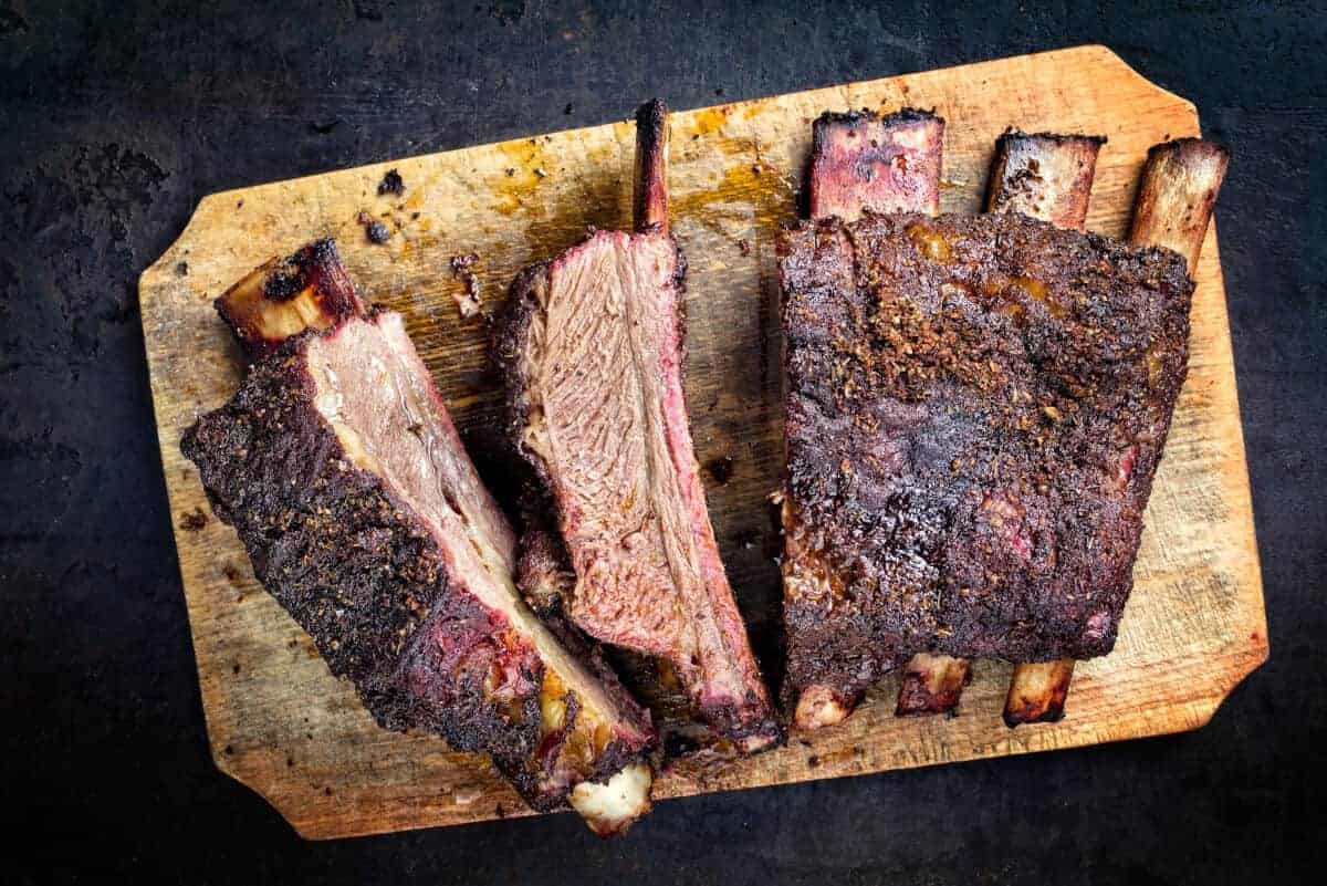 Smoked short ribs, sliced on a wooden cutting bo.