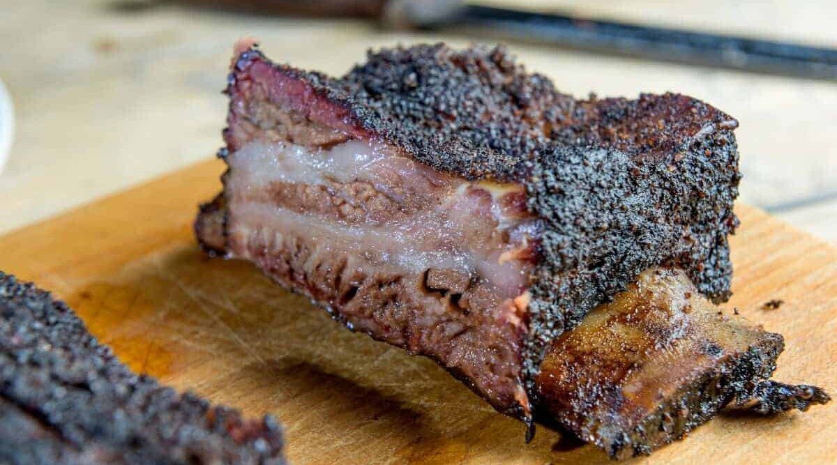 smoked and sliced beef short ribs on a wooden cutting board.