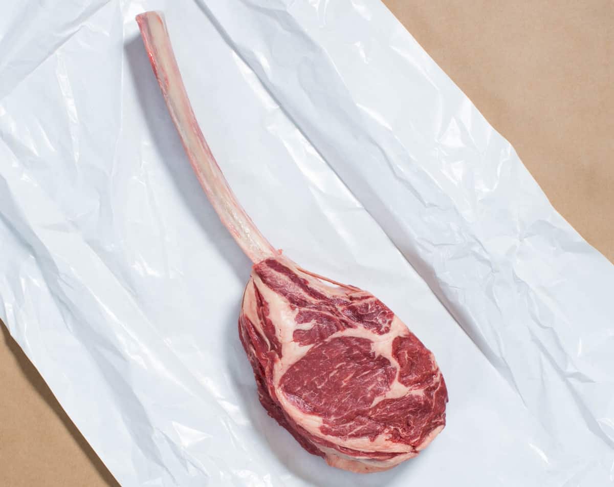 A porter road tomahawk steak on white butcher paper.