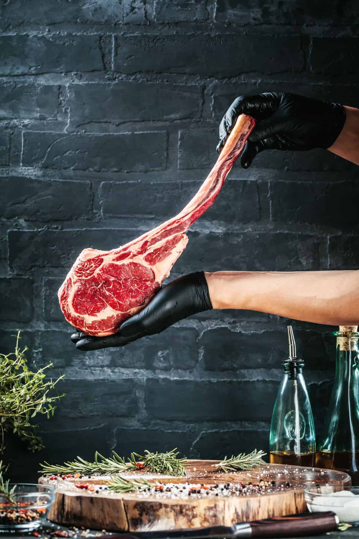 A butchers gloved hands holding up a large tomahawk st.