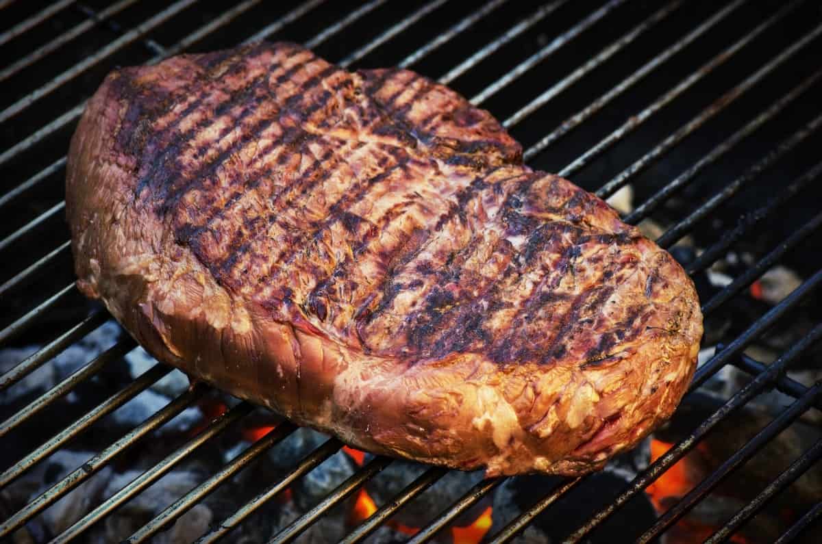 ribeye steak being seared on a charcoal grill