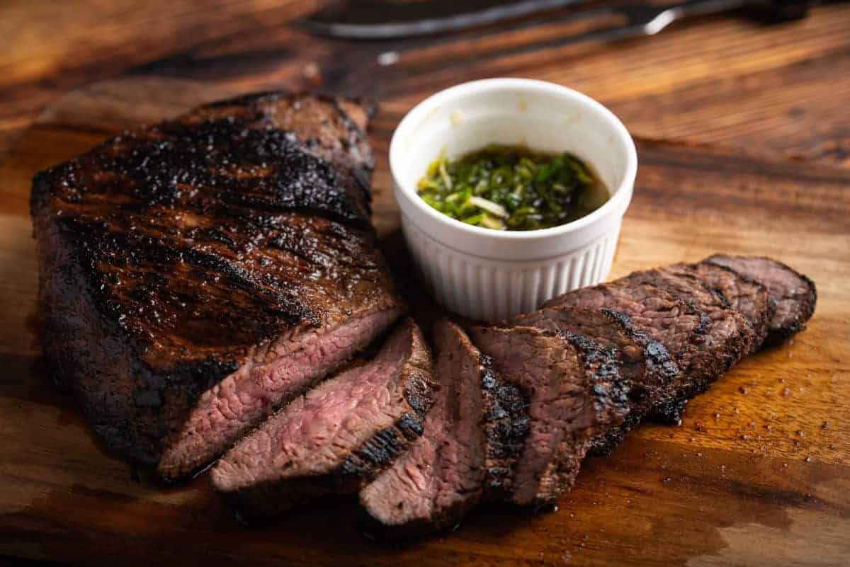 A smoked then sliced tri-tip with a ramekin of chimichu.