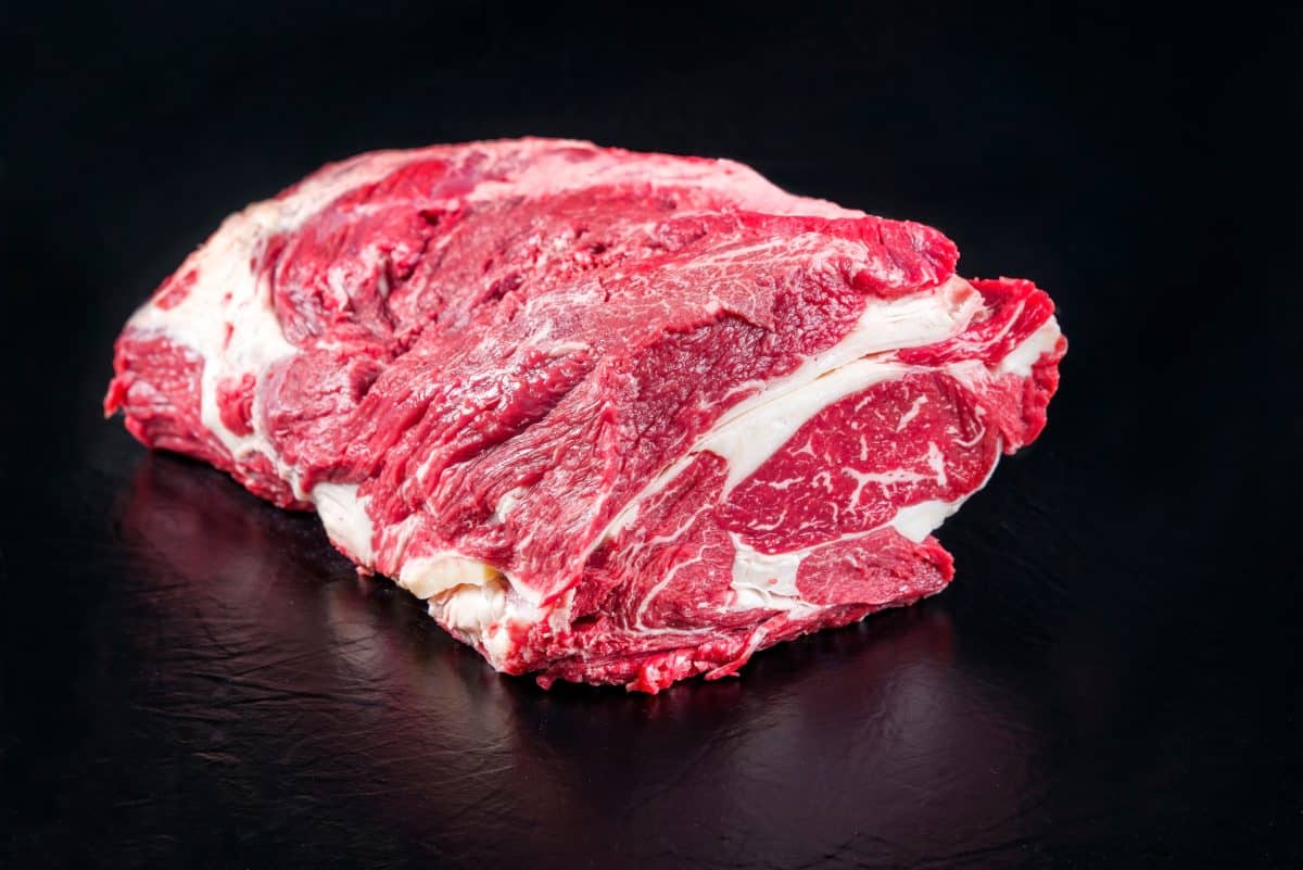 A raw dry-aged wagyu chuck eye roast on a black surface