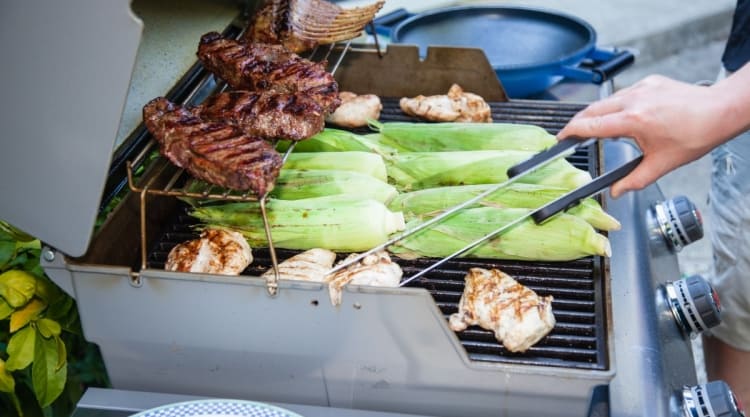 Steak, corn and other items on a large gas grill.
