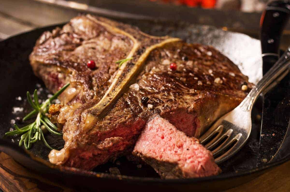 grilled porterhouse steak with a piece cut off and held by a f.