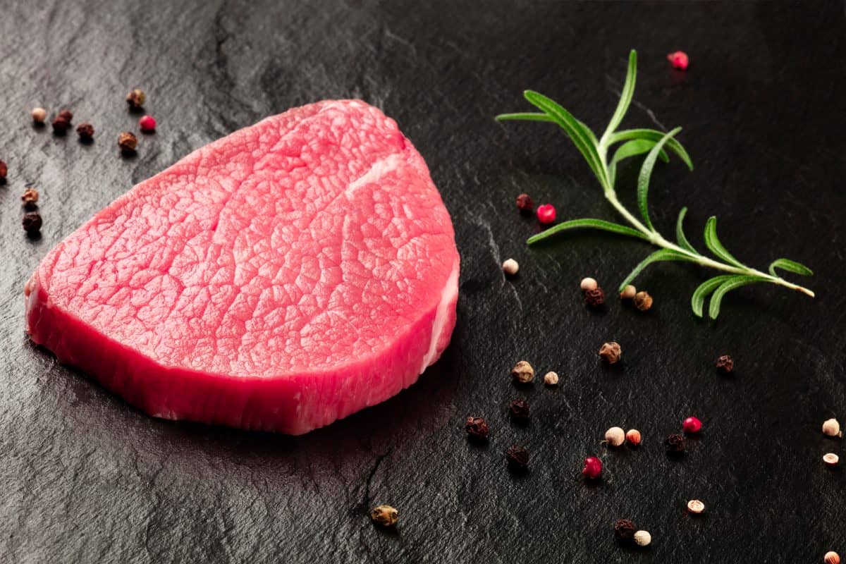 Close up of an round eye steak with rosemary and pepperco.