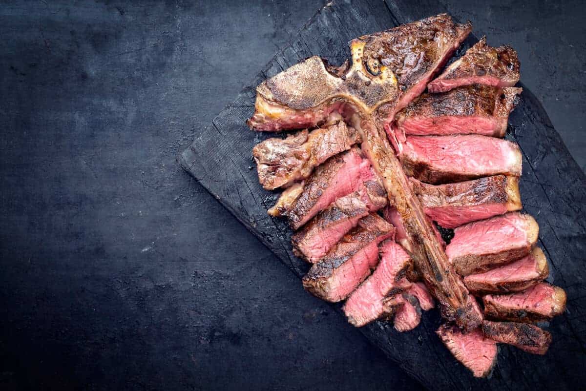 sliced porterhouse steak on a dark backgro.