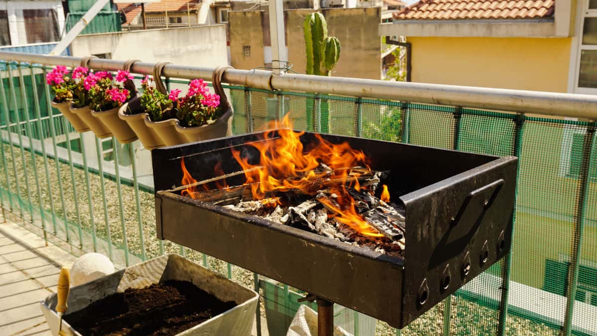 A live fire of wood or charcoal, in a small grill on a balc.