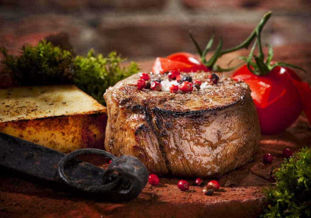 A nicely seared filet mignon steak with tomatoes, herbs and spi.