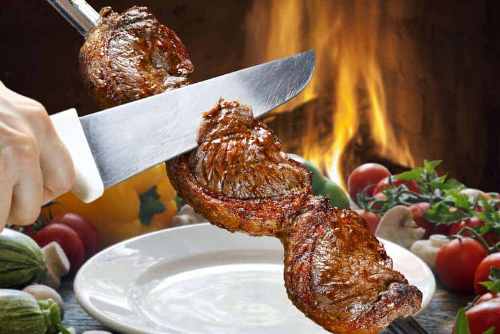 picanha steaks being sliced onto a white pl.