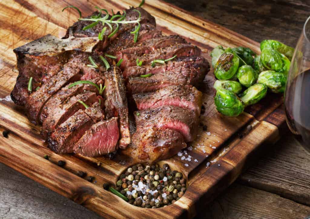 A grilled, sliced porterhouse steak with Brussels spro.