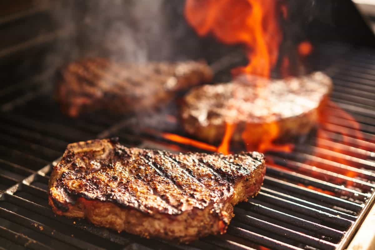 thin steaks grilling, one over flames and one just .