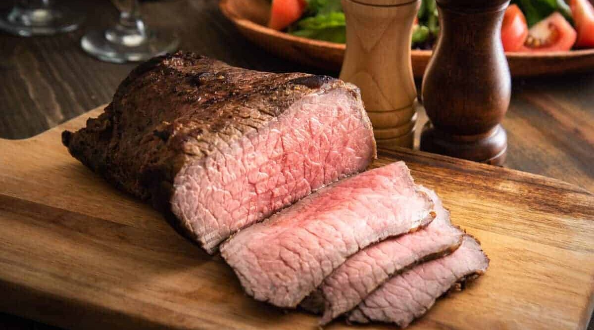 Roasted and sliced bottom round roast on a cutting board.