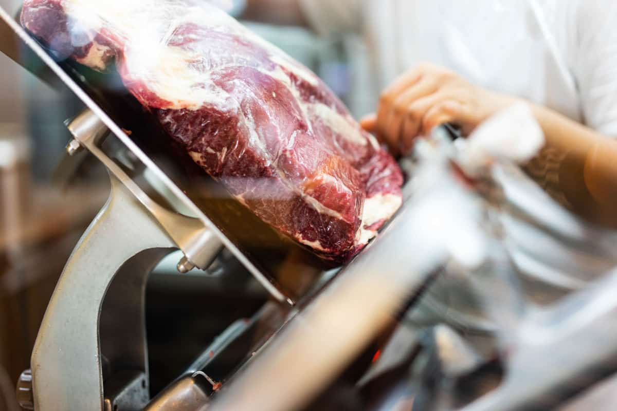 A huge piece of beef in a commercial meat sli.