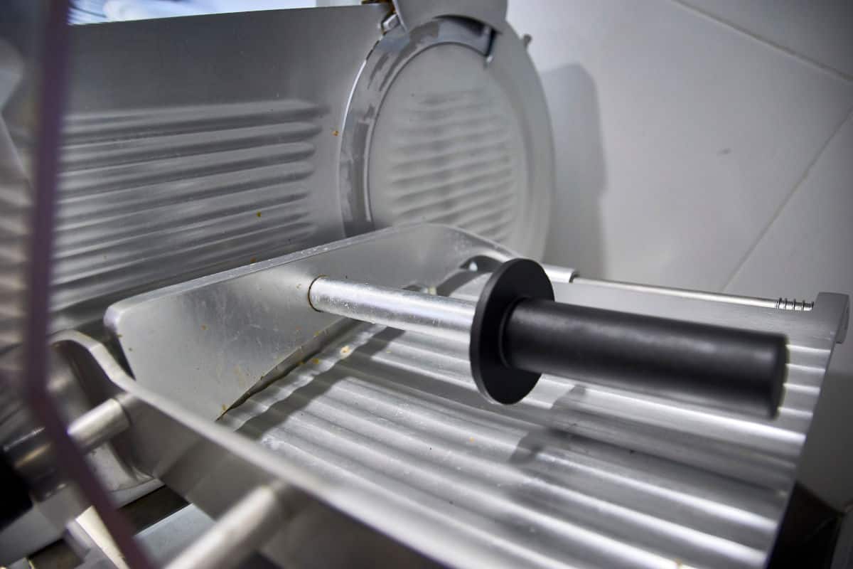 Close up of a meat slicers food carri.