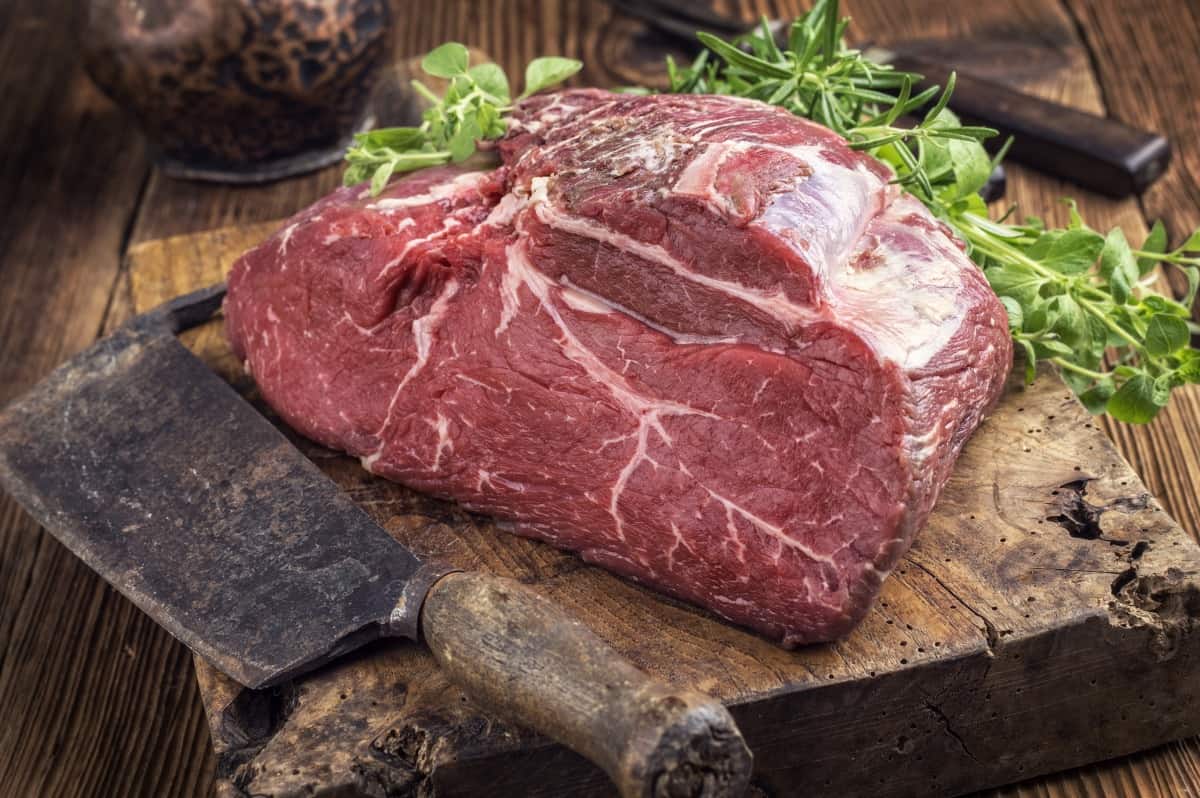 raw bottom round roast with meat cleaver on cutting board
