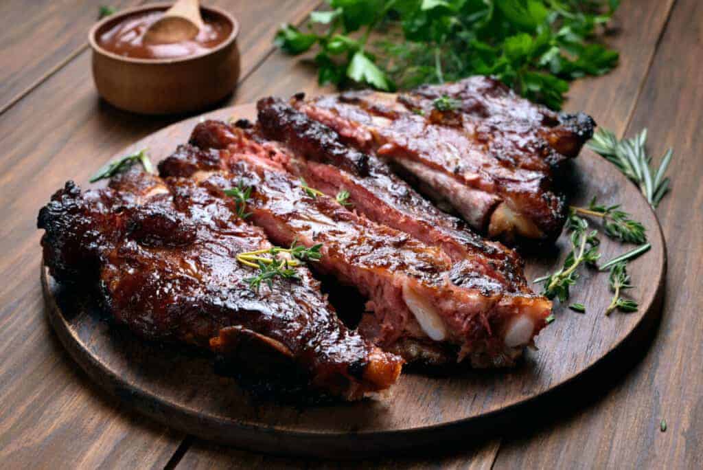 BBQ spare rib platter with rosemary and a pot of sa.
