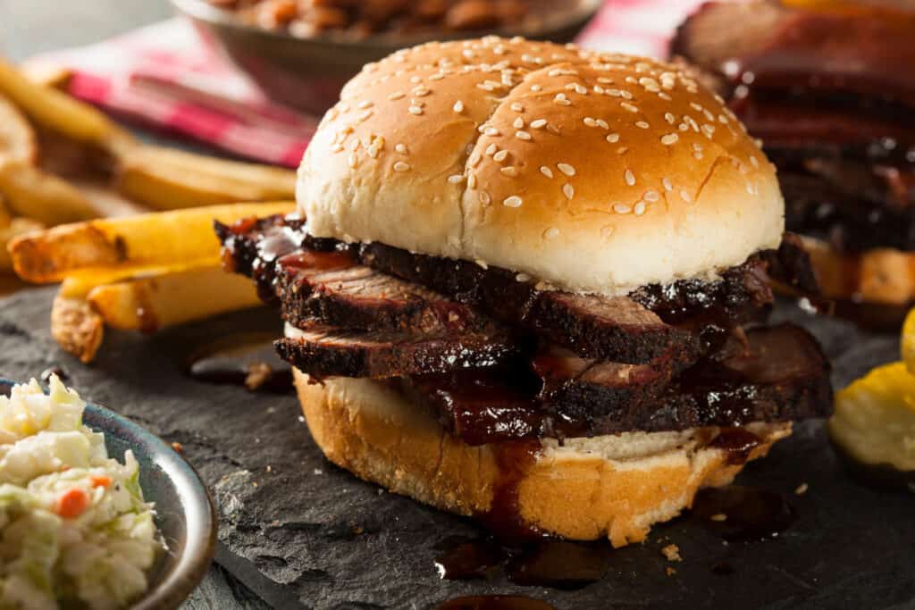 Smoked BBQ brisket in a seeded roll with some sides