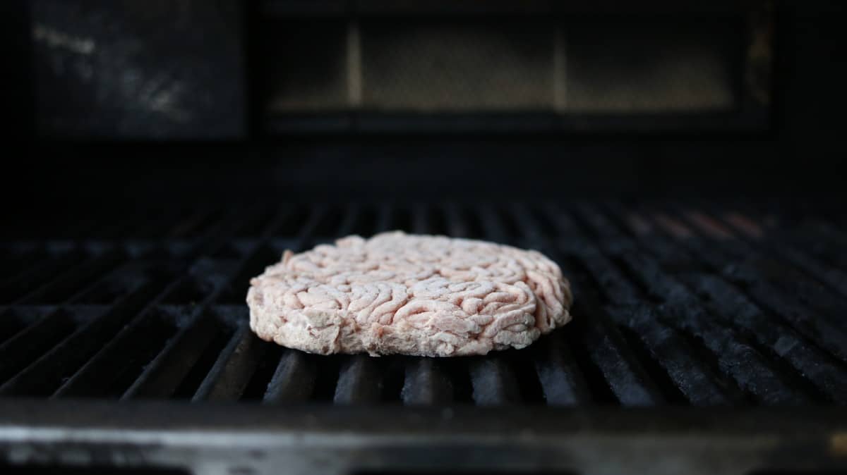 Close up of a frozen burger on some grill grates
