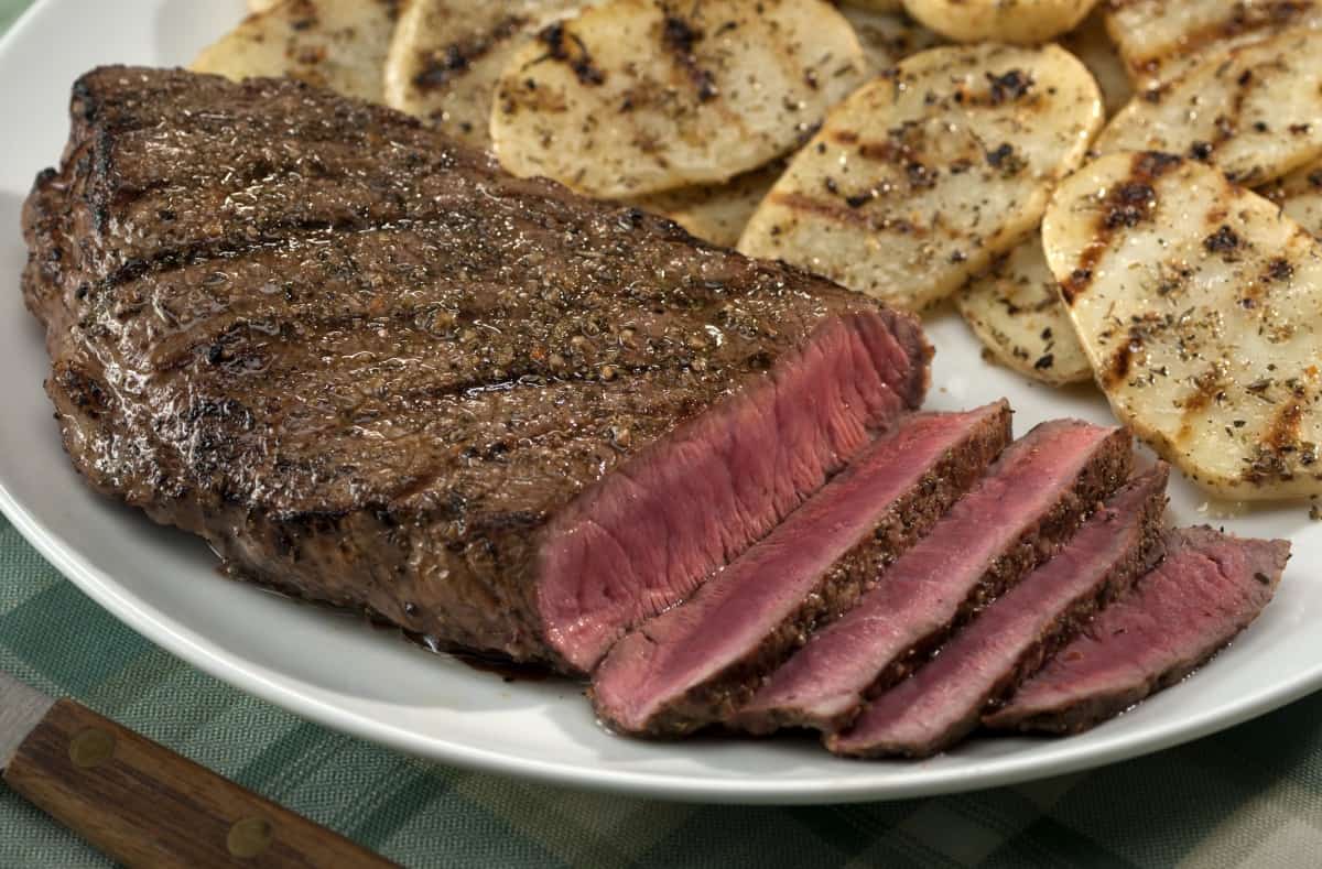 grilled and sliced top round steak with thin grilled potat.