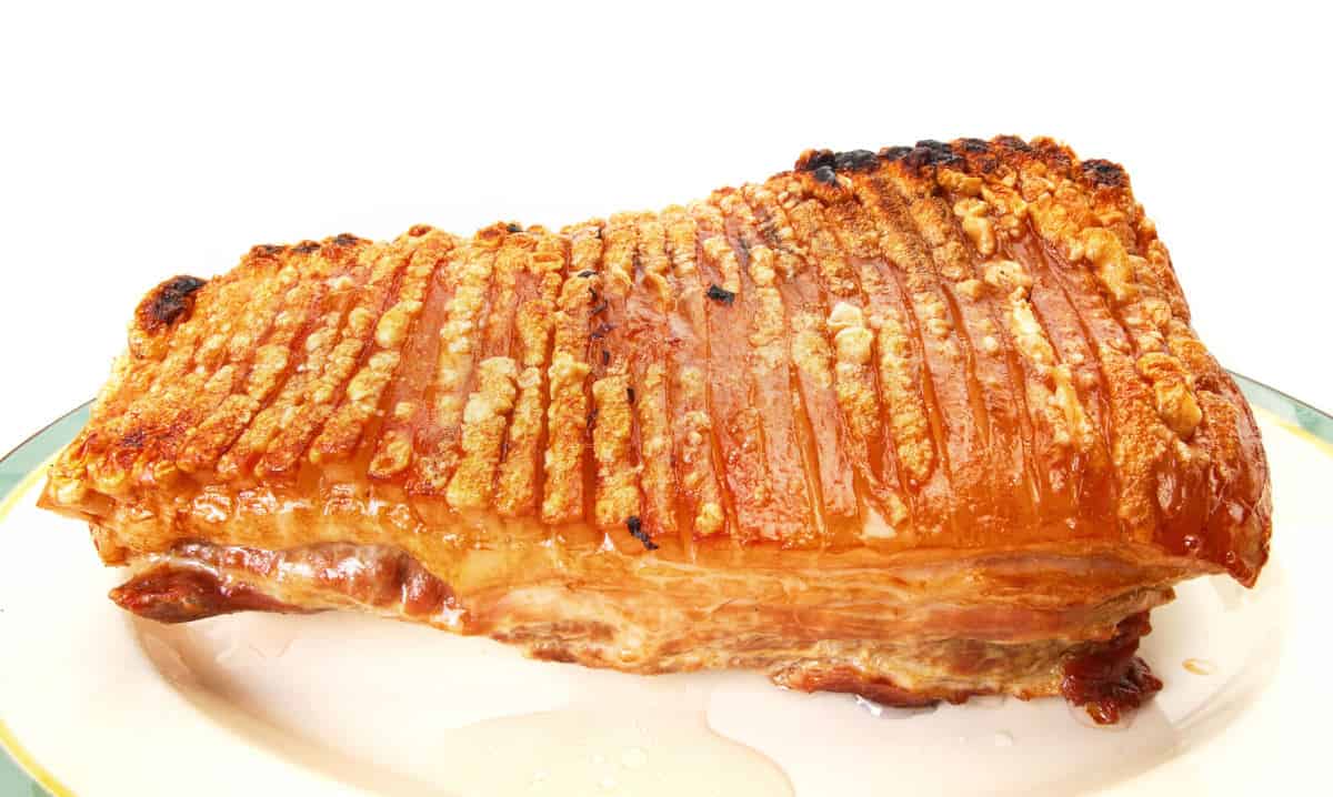 A pork roast with crispy skin isolated on white