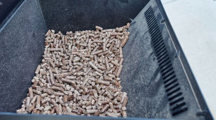 A pellet grill hopper half full of smoking wood pellets.