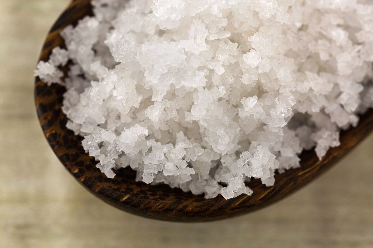 A close up of some Fleur Se Sel salt on a wooden sp.