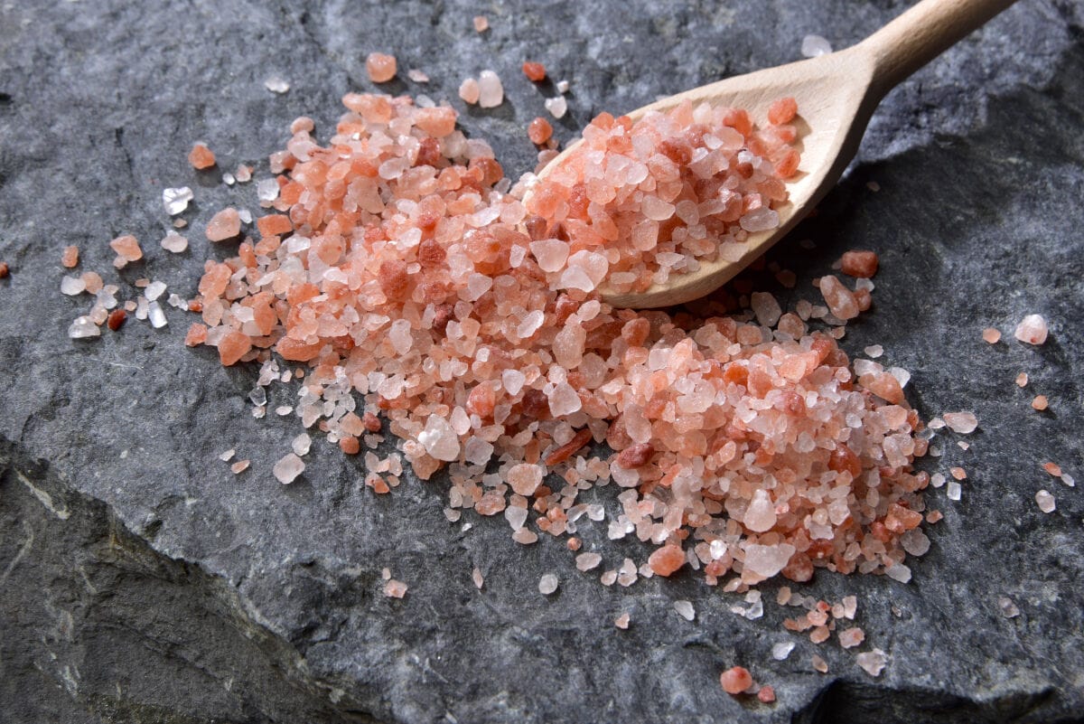 A pile of ink Himalayan sea salt with some on a wooden sp.