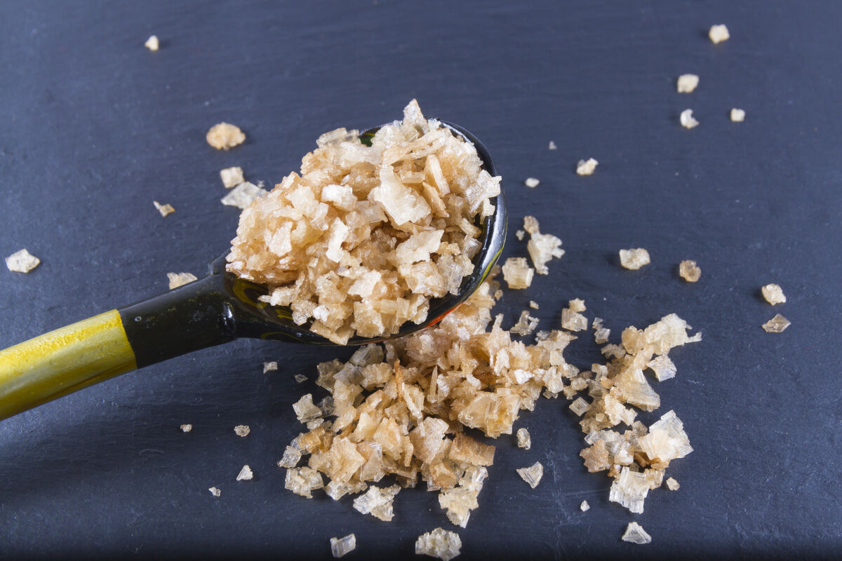 A spoon full of smoked sea salt, some spilled onto the ta.