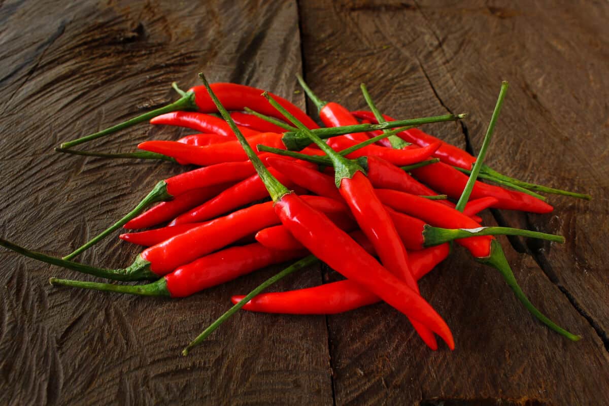 A pile of birds eye chilies on a wooden ta.