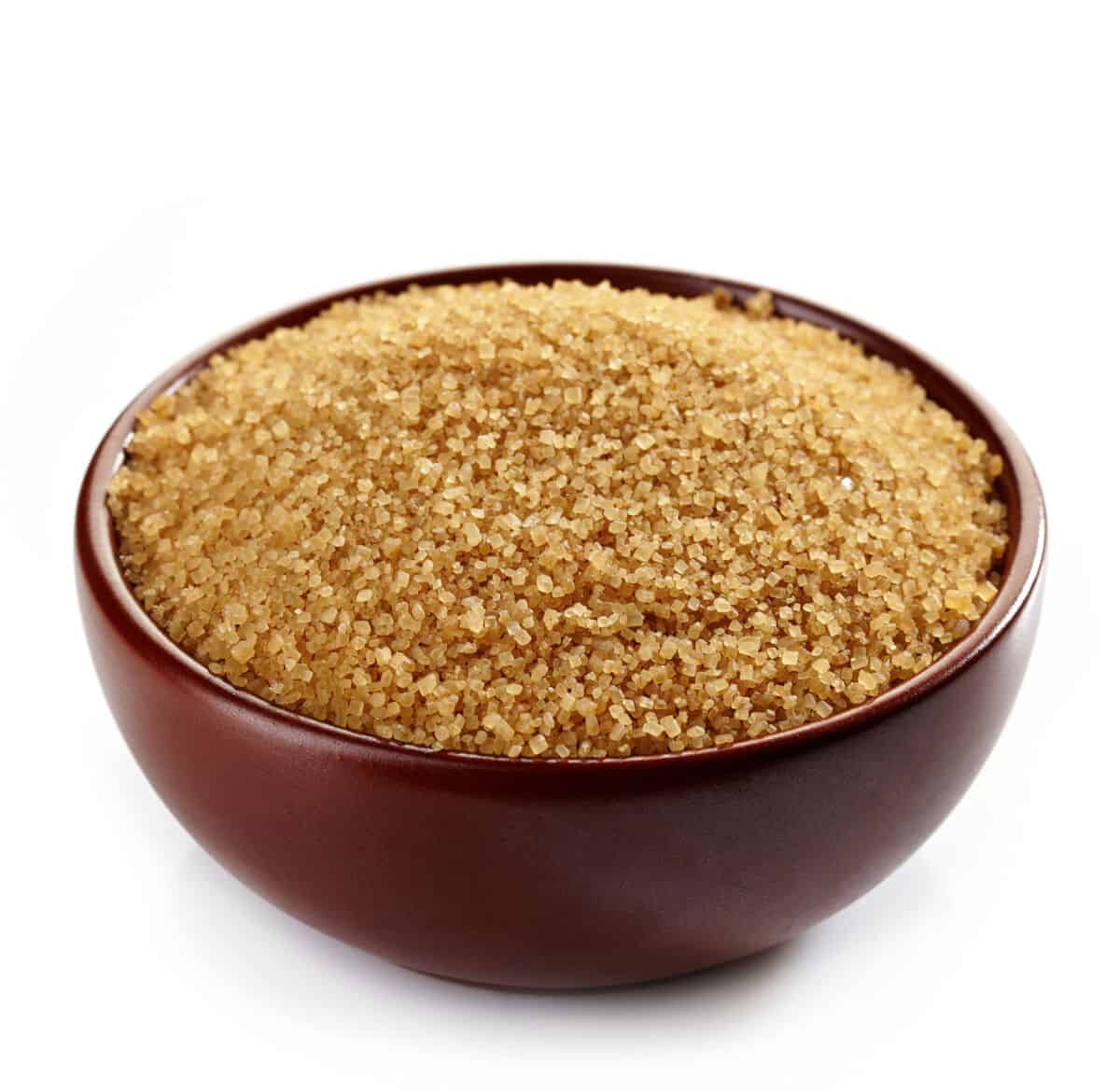 A brown bowl full of granulated brown sugar isolated on wh.