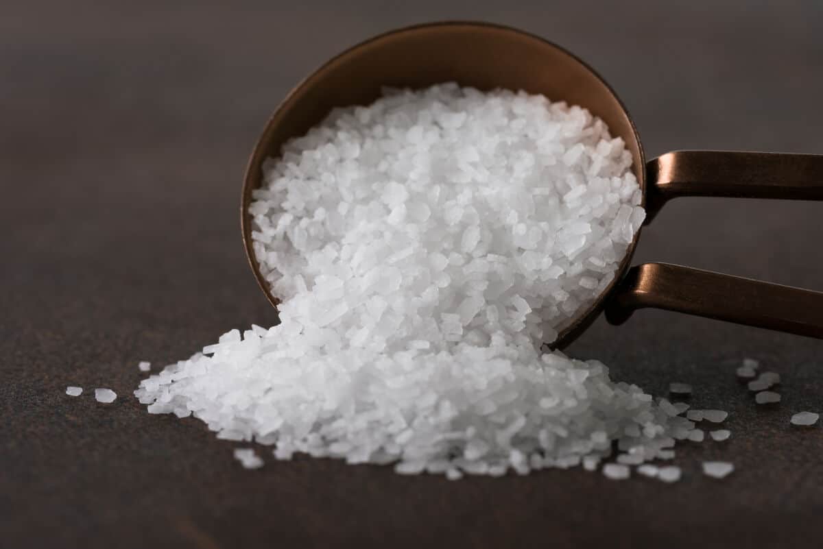 A bowl of kosher salt spilling out onto the ta.